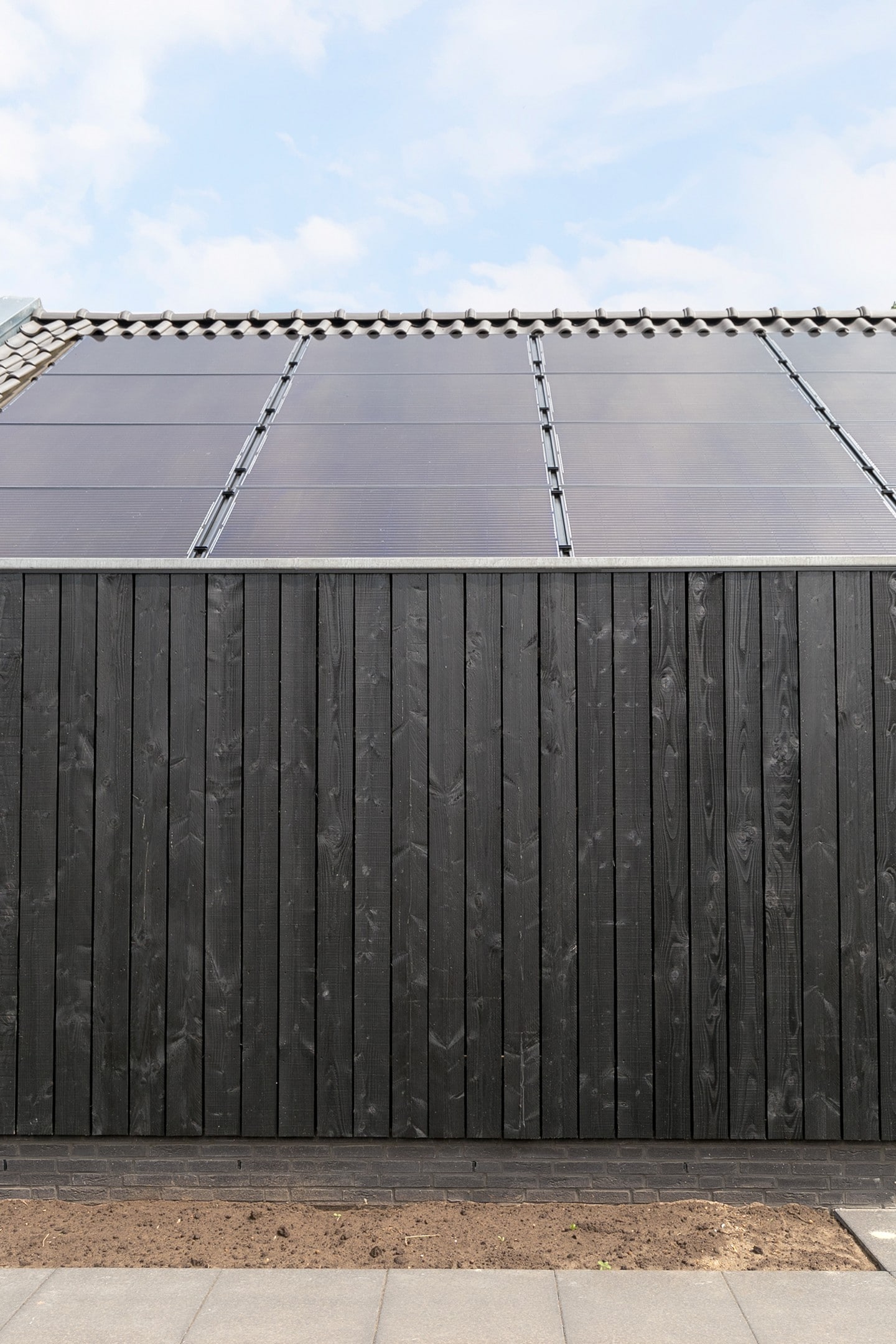 De zwarte houtengevelbekleding en zonnepanelen op het dak